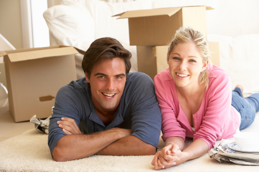 Young Couple Moving Into New Home Surrounded By Packing Boxes